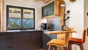 Una cocina moderna con un ventanal grande, armarios de madera, una mesa de comedor de madera y una silla.