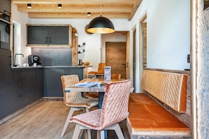 Une cuisine moderne avec des meubles de couleur sombre, une machine à café et un coin repas comprenant une table et des chaises rembourrées.