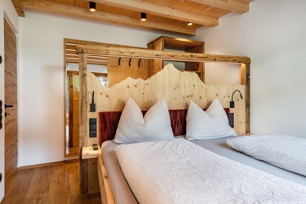 Une chambre avec une tête de lit en bois, deux lits, un miroir et un plancher en bois.
