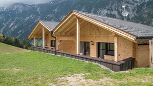 Una cabaña de madera con balcón, ventanas amplias y una antena parabólica.