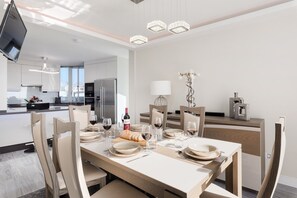 A modern dining area with a table set for four, a kitchen in the background, and a decorative plant on the table.