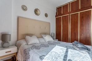 A bedroom with a large bed, two bedside tables, a wooden wardrobe, and decorative wall art.