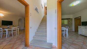 A staircase leading to a second floor, a dining area with a table and chairs, and a kitchen area with cabinets and a countertop.