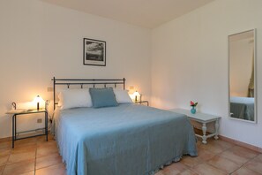 Un dormitorio con cama, mesitas de noche, tocador, espejo y un cuadro en la pared.
