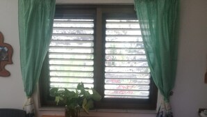 A small dining area with a wooden table and two stools, a window with blinds, and a potted plant on the windowsill. - Holiday Home "Casa Grenado" with Sea Views, Private Balcony & Wi-Fi (vallehermoso tazo)