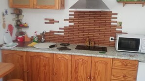 A kitchen with wooden cabinets, a stainless steel range hood, a microwave, and a tiled floor. - Holiday Home "Casa Grenado" with Sea Views, Private Balcony & Wi-Fi (vallehermoso tazo)