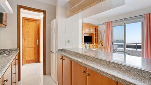 A kitchen with granite countertops, wooden cabinets, a built-in stove, and a view to a balcony with a table and chairs.