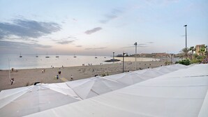 A beach with umbrellas, a sandy shore, and boats in the water.