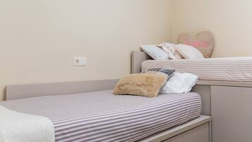 A single bed with striped bedding, a headboard, and a bedside drawer.