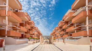 Un immeuble d’appartements moderne doté de nombreux balcons, d’une allée centrale et offrant une vue sur un ciel dégagé.