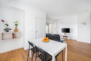 A modern living room with a white dining table, black chairs, a TV, and a sofa. - Apartment 'Lopimar Bonito' with Mountain View, Wi-Fi and Air Conditioning (Canet de Berenguer)
