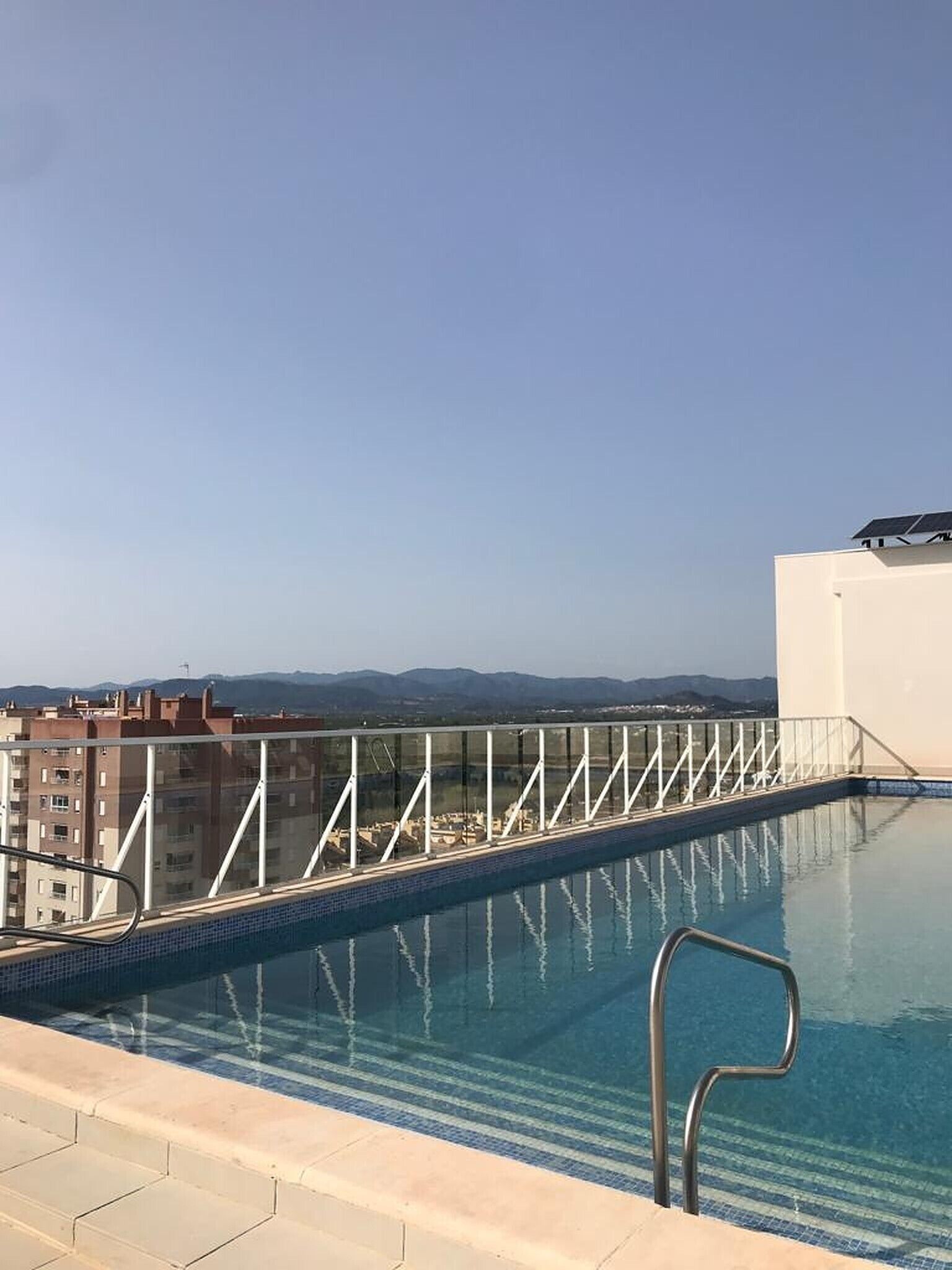 Una piscina en la azotea con vistas despejadas del paisaje urbano y montañas a lo lejos.