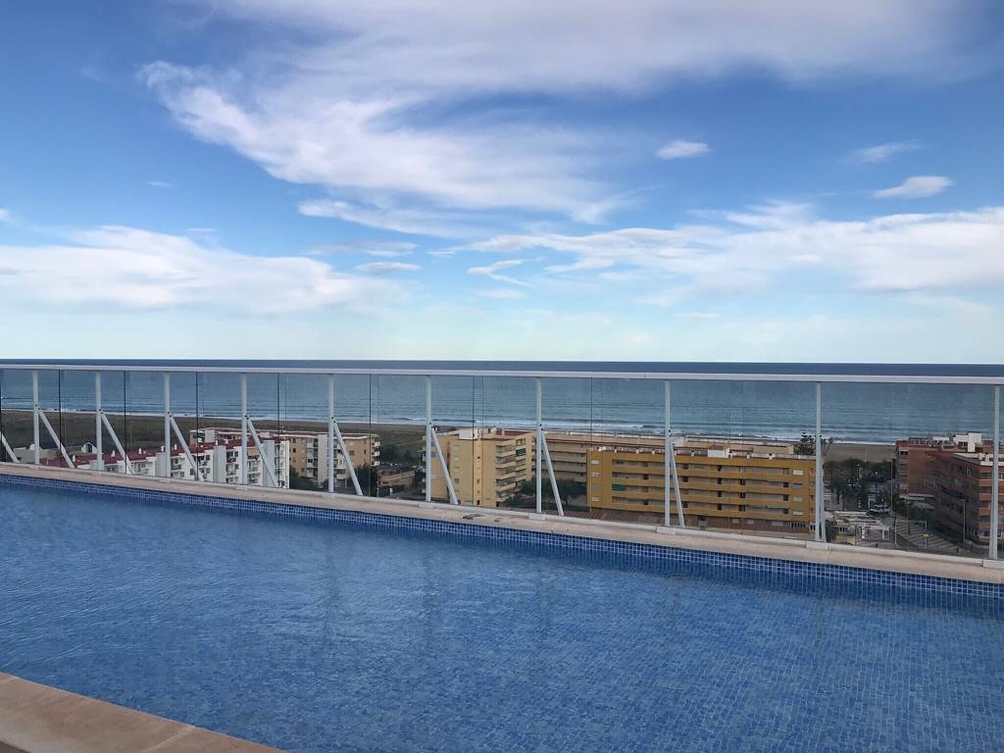 Una piscina con vista al océano y edificios al fondo.
