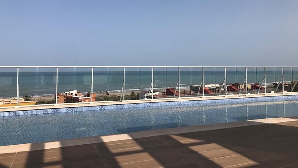 Une piscine avec vue sur l’océan et des bâtiments en arrière-plan.