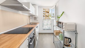 Une cuisine moderne avec un plan de travail en bois, des appareils en acier inoxydable et une vue sur un immeuble par la fenêtre.