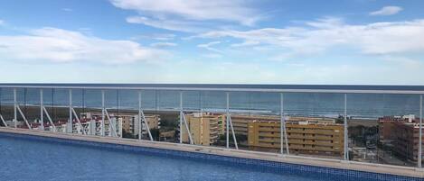 Una piscina con vista al océano y edificios al fondo.