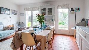 Comedor con mesa dispuesta para cuatro, un armario blanco con puertas de cristal y vista a zonas verdes.