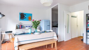 Un comedor con una mesa lista para dos, un refrigerador azul y un cuadro colgado en la pared.