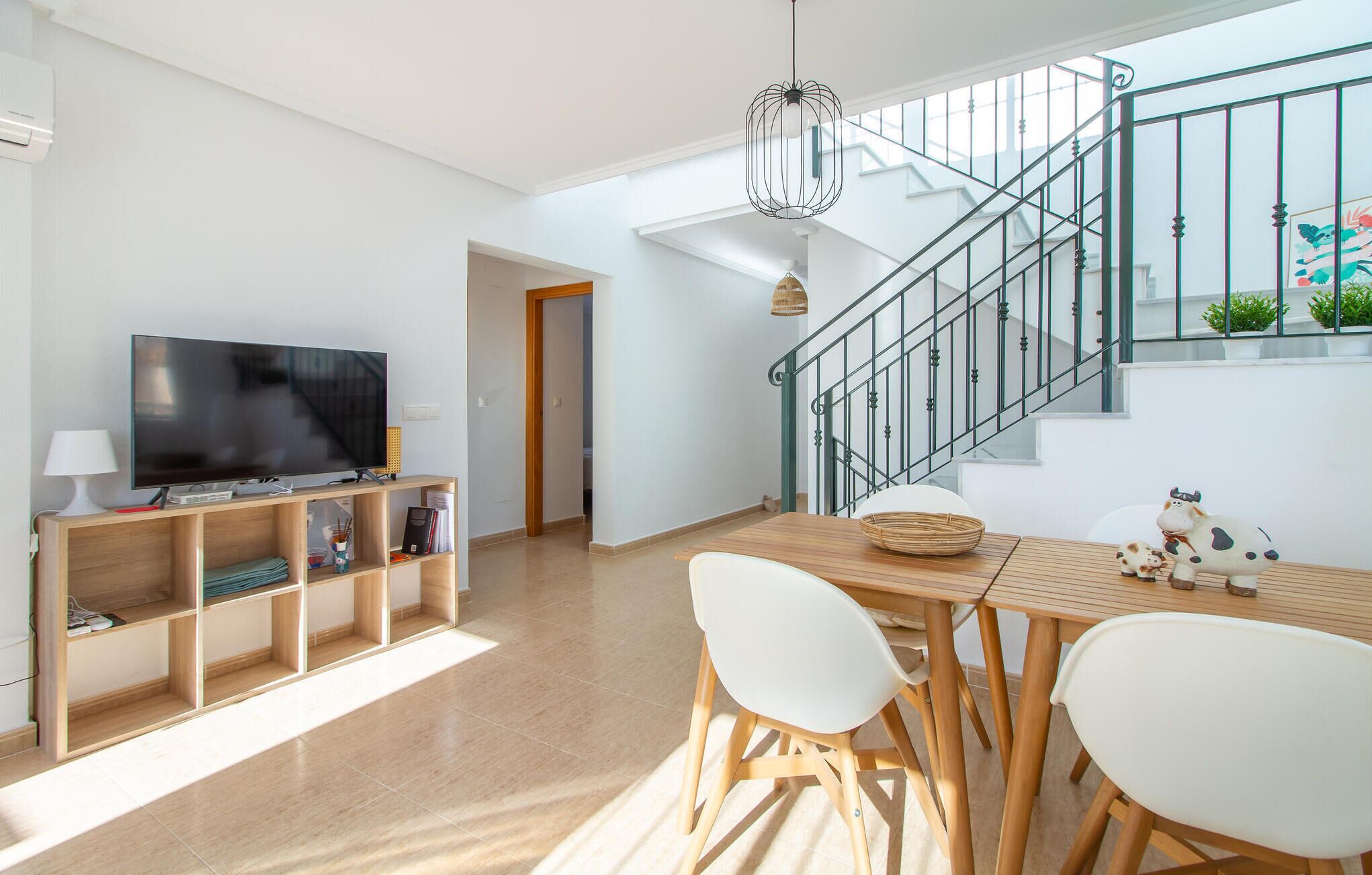 Un salon moderne doté d’un téléviseur à écran plat, de meubles en bois, d’un escalier et offrant une vue sur l’extérieur.