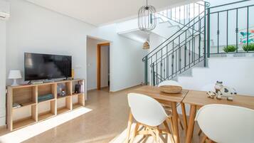 Un salon moderne doté d’un téléviseur à écran plat, de meubles en bois, d’un escalier et offrant une vue sur l’extérieur.