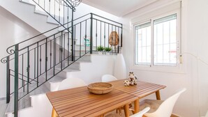 A staircase with a metal railing, a wooden table with chairs, and a window with blinds.