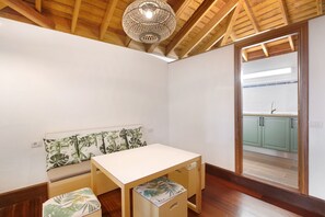 A room with a wooden ceiling, a white table, a bench with a leaf-patterned cushion, and a view of a kitchen through a doorway. - 'Casa rural Dragomar' with Sea View, Shared Terrace and Wi-Fi (Tacoronte)