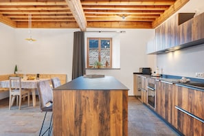Une cuisine moderne avec des meubles en bois, un îlot central et un coin repas comprenant une table et des chaises.