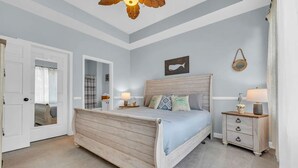 Et soveværelse med en træseng, sengeborde, en loftsvifte og en vægmonteret lampe.