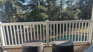 En balkon med fletmøbler, gelænder i hvidt og udsigt til en sø.
