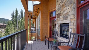 A wooden deck with two chairs and a small table, overlooking a mountainous area. - Luxury 2BD Village at Northstar Residence w/ Ski Valet (Truckee)