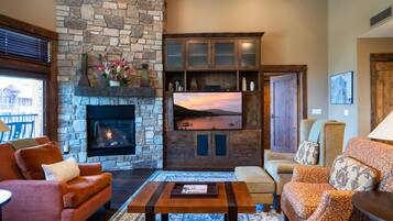 A cozy living room with a stone fireplace, comfortable seating, and a television.