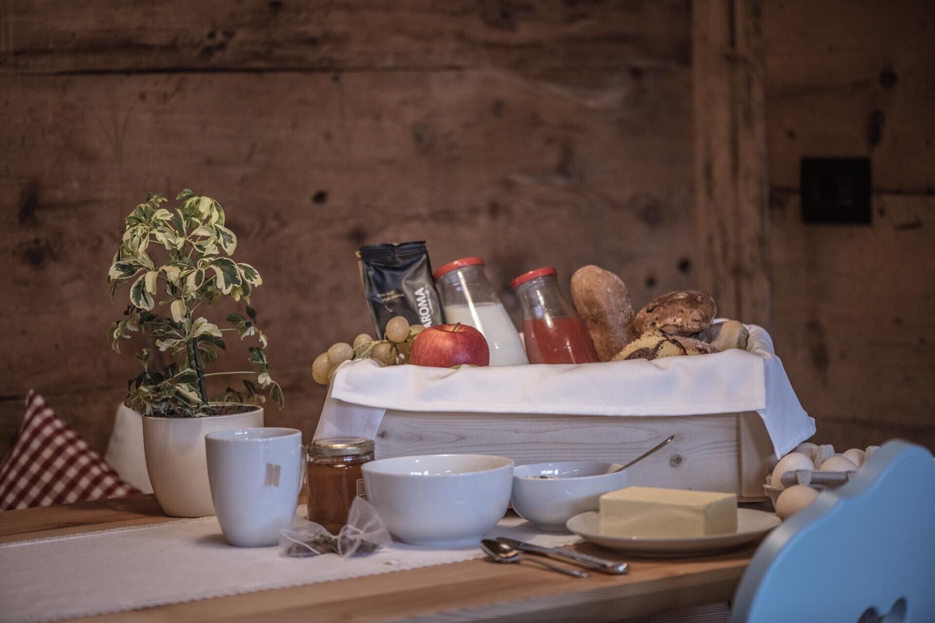 Una mesa de madera con diversos alimentos, una planta en maceta y utensilios de cocina.