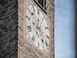 Une horloge à chiffres romains fixée à un mur de pierre.