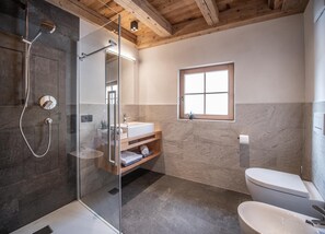 Une salle de bain moderne avec une douche à parois de verre, un meuble-lavabo en bois, des toilettes et une fenêtre.