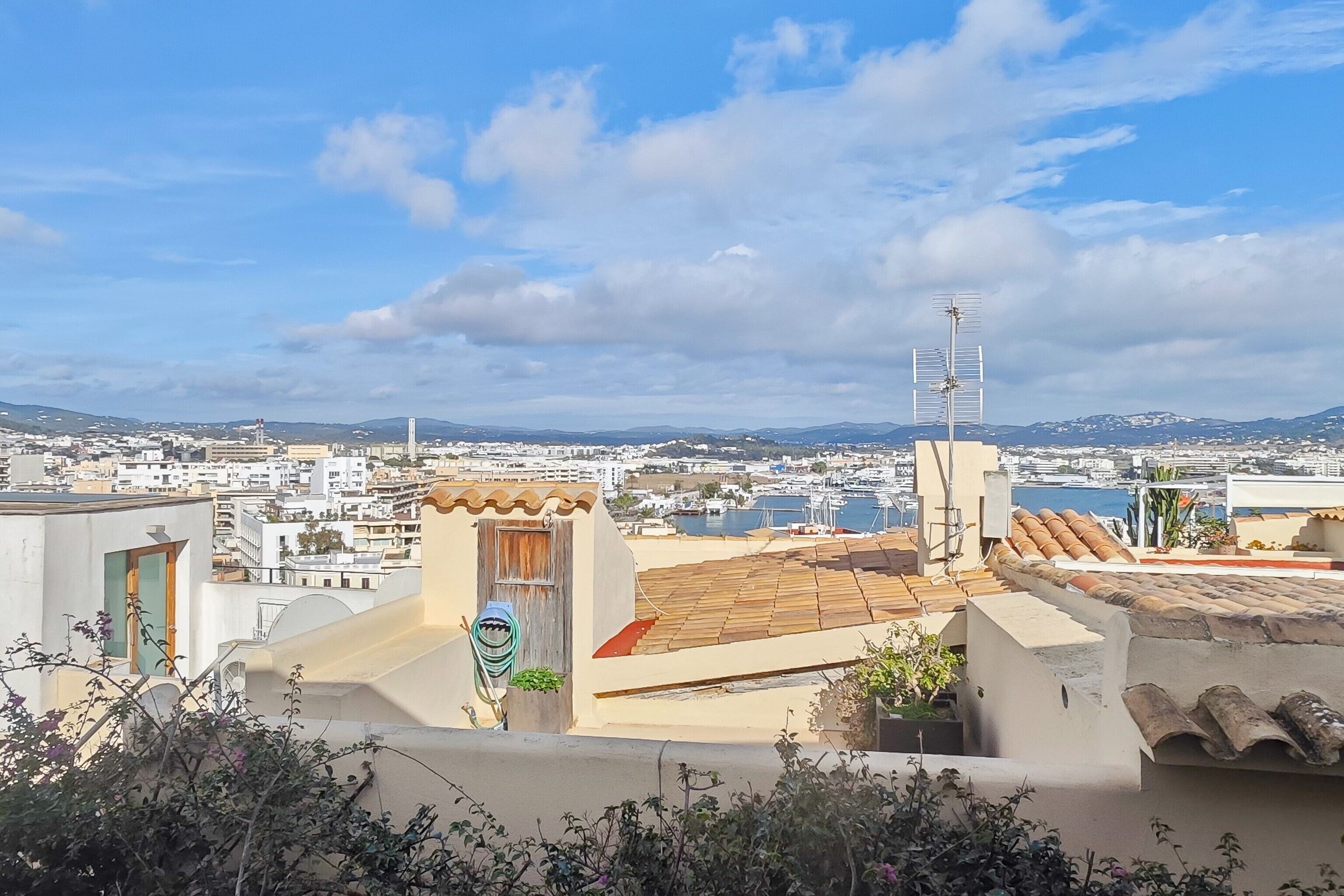 A rooftop terrace with a view of a coastal cityscape, including a marina and distant mountains.