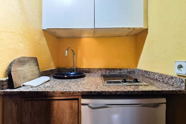 A compact kitchen with a granite countertop, a built-in sink, a stove, and wooden cabinets. - Apartment 'Navila' with Shared Pool, Wi-Fi and Air Conditioning (Eivissa)