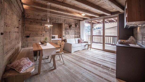 Ein rustikales Holzinterieur mit Essbereich, Sofa und einem Balkon mit Blick.