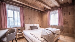 Ein Zimmer aus Holz mit einem Bett, einem Sessel und einem Tisch.