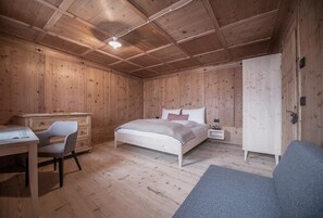 A wooden room with a bed, a desk, and a chair.
