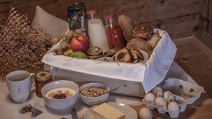 Ein Frühstücksbuffet mit Brot, Früchten, Eiern und Milchprodukten auf einer Holztischplatte.