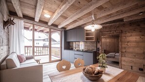 Ein gemütliches Blockhaus-Interieur mit Essbereich, einer Couch, einer Küche und einem Balkon.