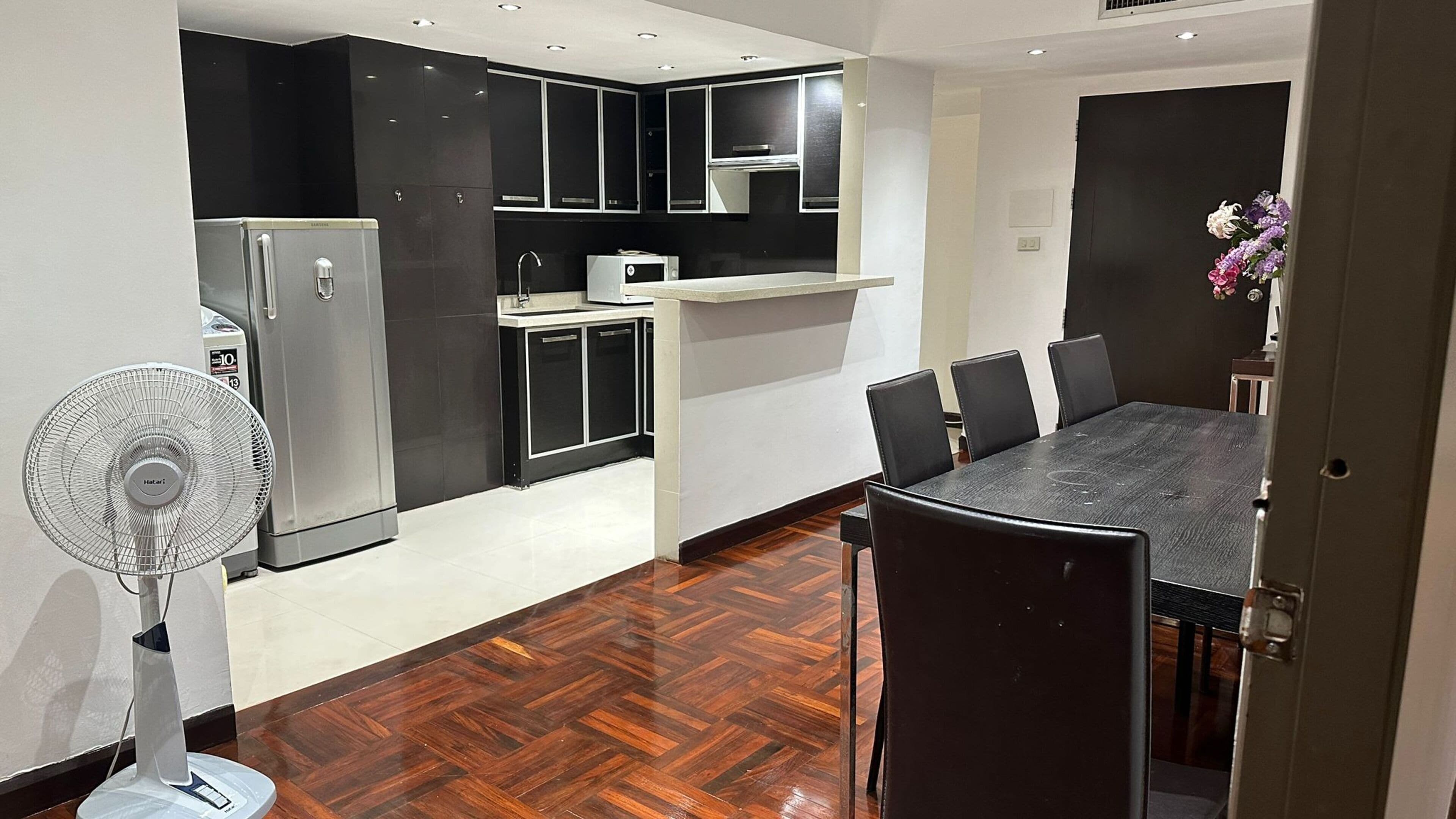 A modern kitchen with a refrigerator, microwave, and a dining area with a table and chairs.
