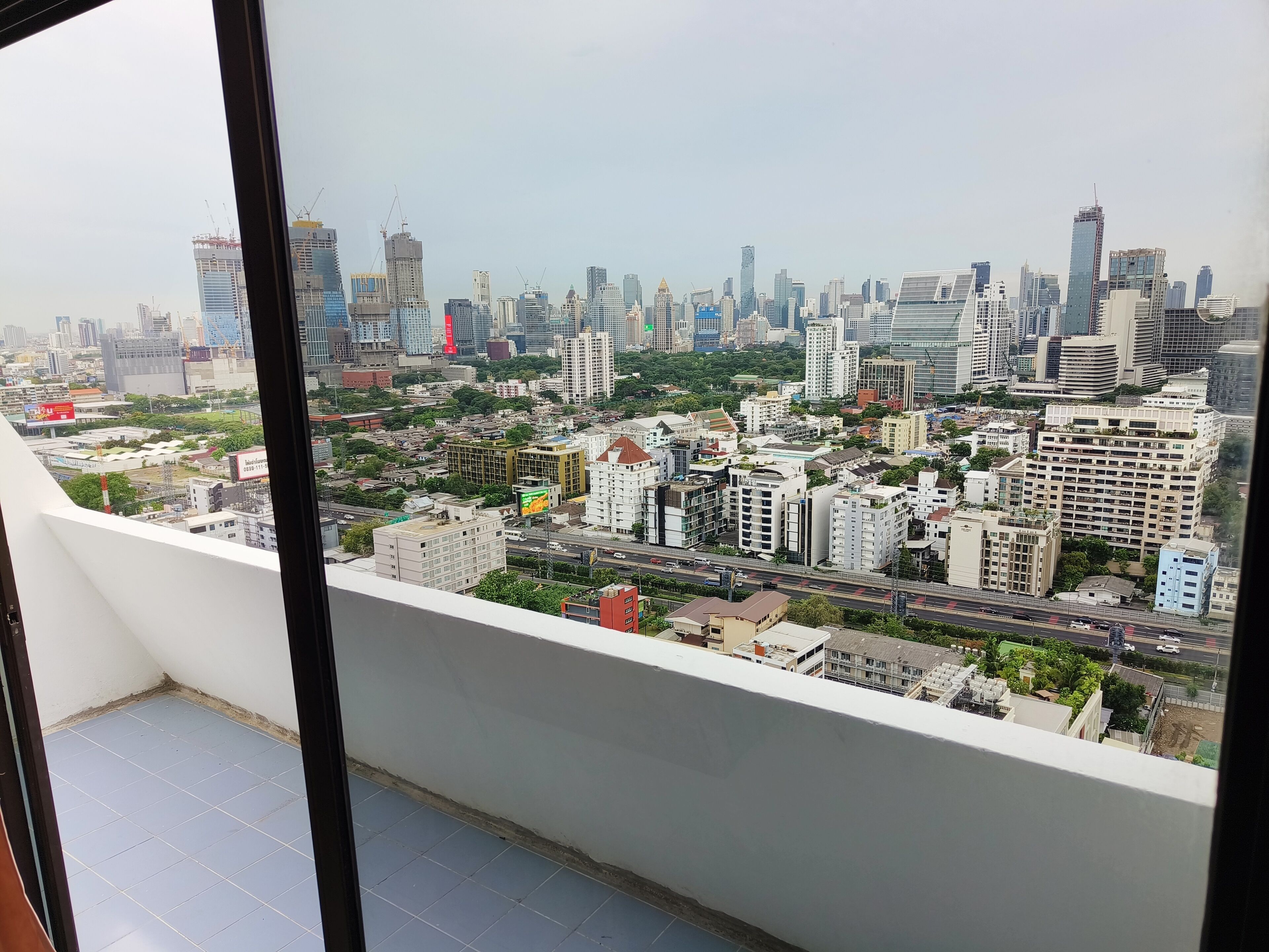A cityscape view from a high-rise building with multiple buildings, roads, and greenery.