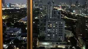 A nighttime cityscape viewed through a window with a metal frame. - Omni Tower Sukhumvit Nana - Direct (Bangkok)