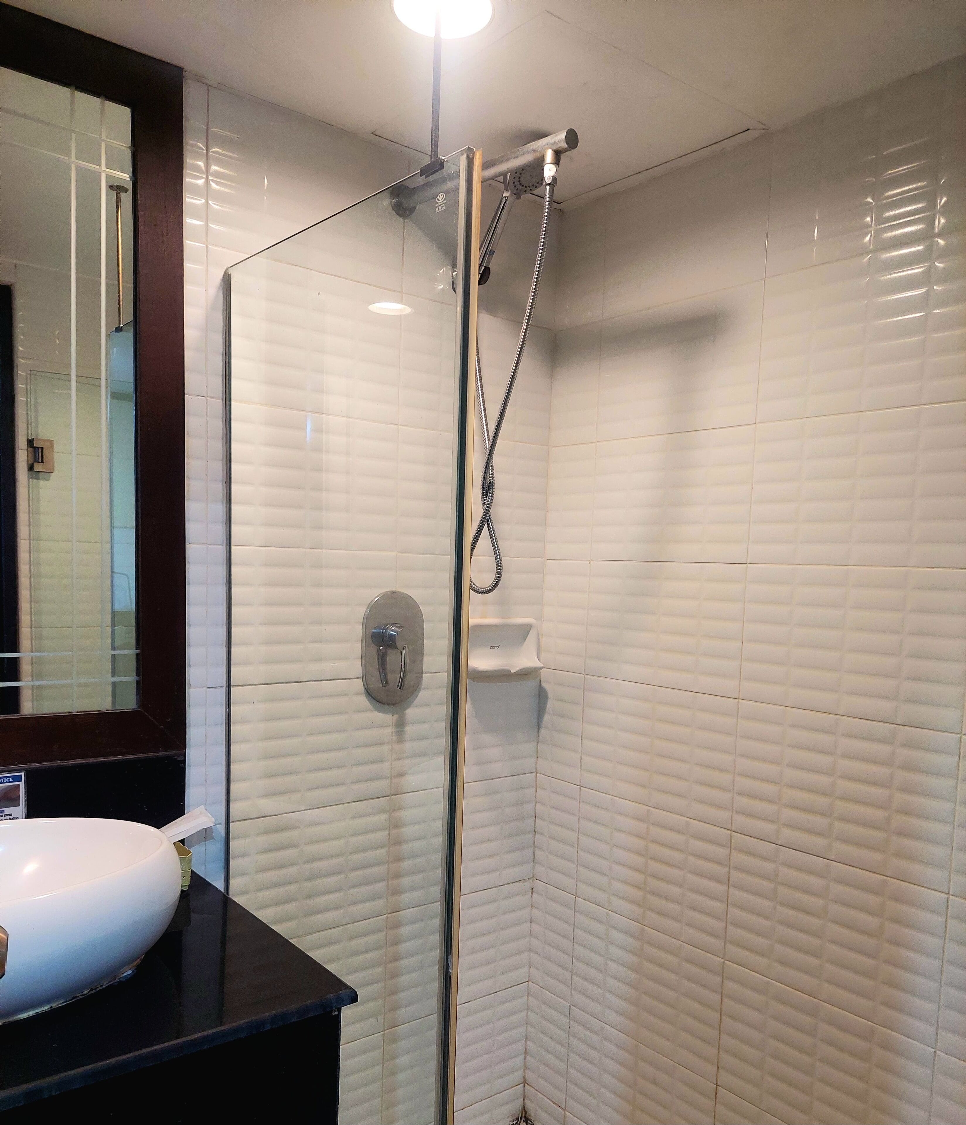 Ein Badezimmer mit einer gläsernen Duschkabine, einem weißen Waschbecken und einem Spiegel darüber.