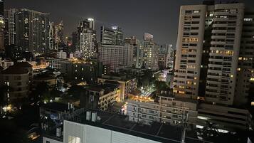 A nighttime cityscape with high-rise buildings, illuminated windows, and a mix of architectural styles.