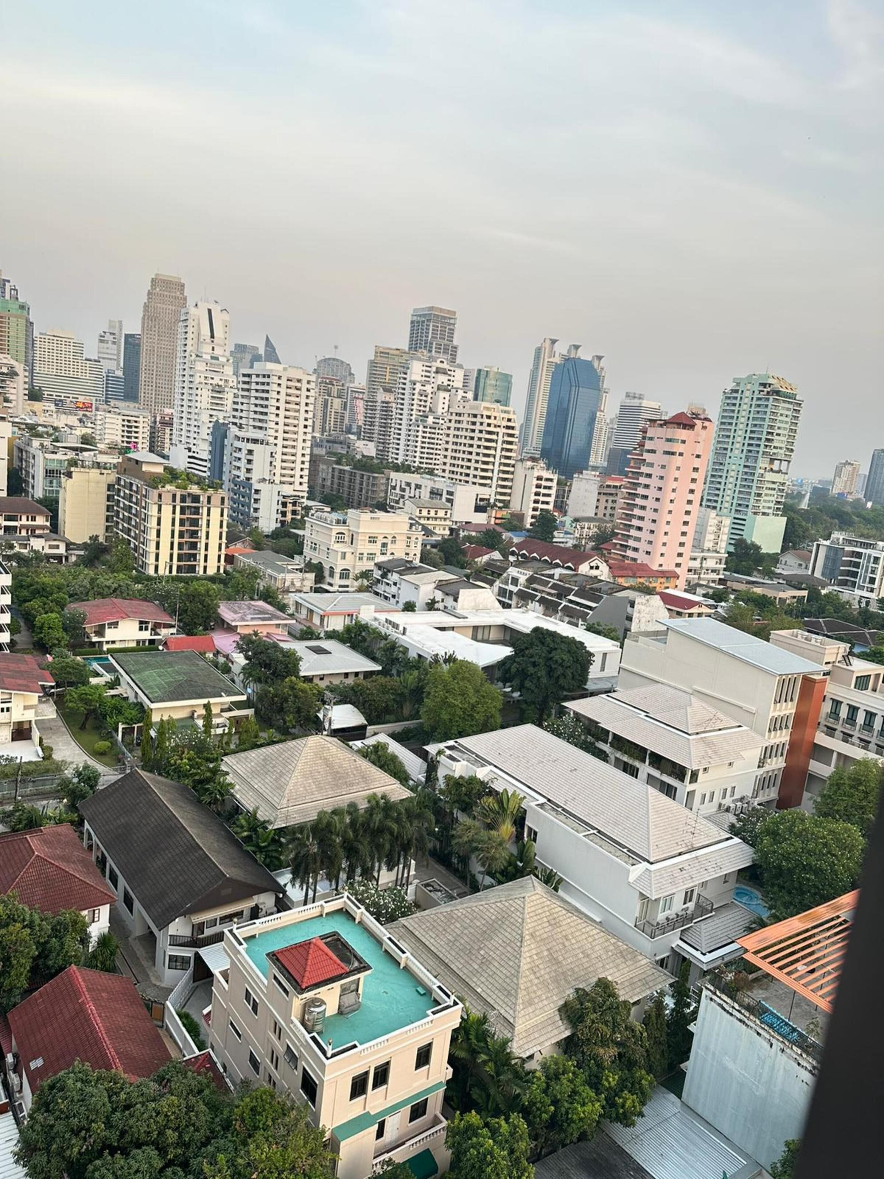 A high-rise building with a rooftop pool, surrounded by other residential and commercial buildings.