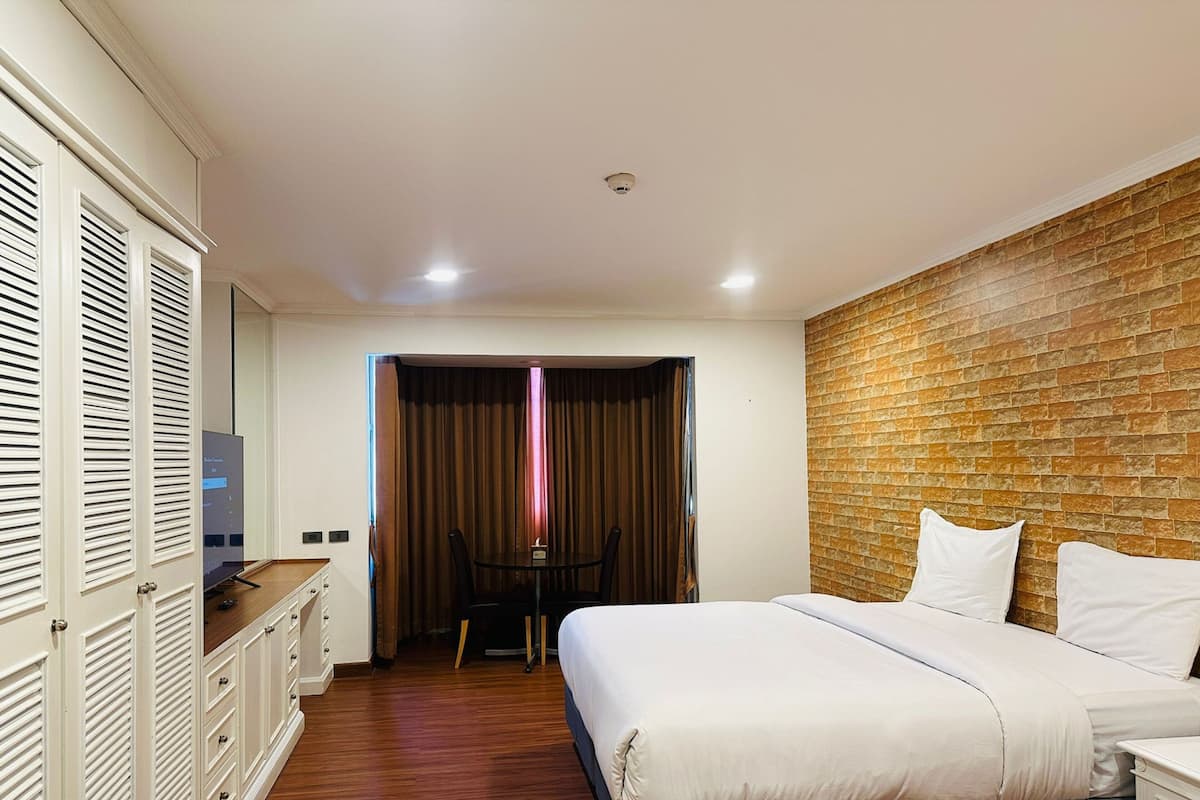 A hotel room with a bed, a desk, a chair, and a wardrobe.