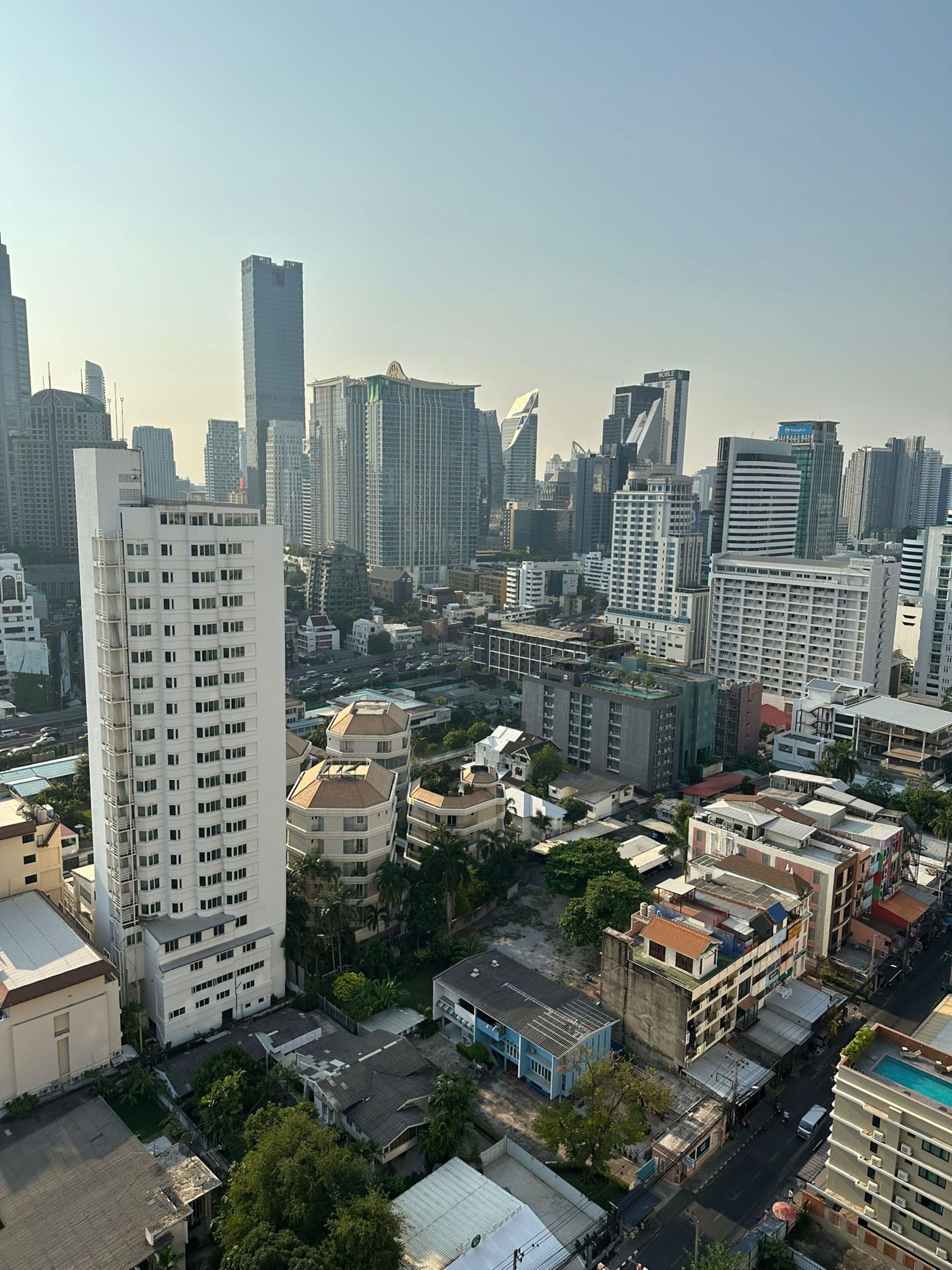 A high-rise building with a modern architectural design, surrounded by other mid-rise buildings and residential structures.