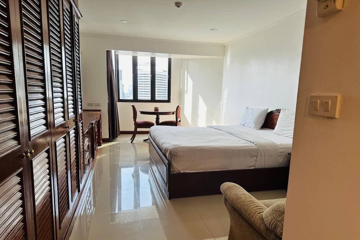A hotel room with a bed, a desk, and a chair.